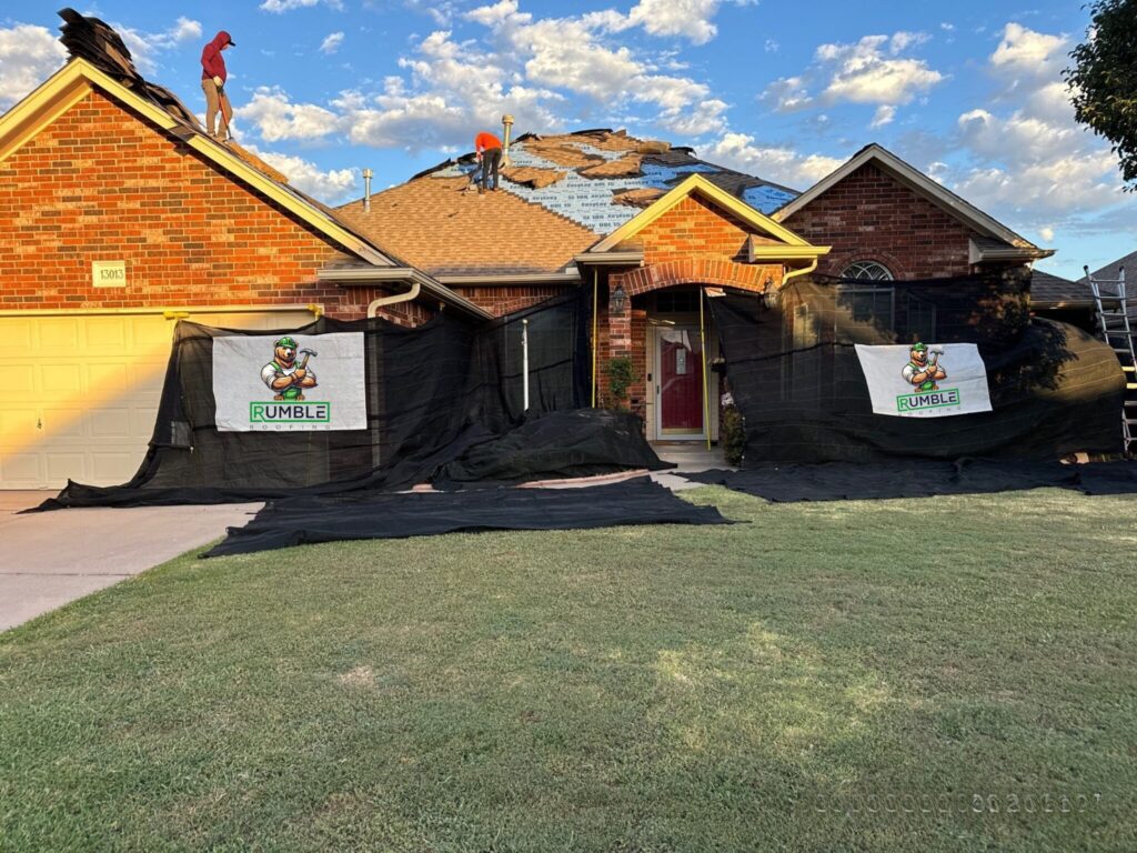 Residential roof replacement in progress with workers and home protection